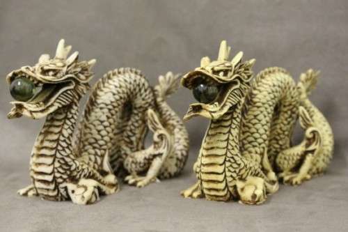 A stunning pair of Japanese ivorine resin dragons figurines with a crystal ball in their mouths