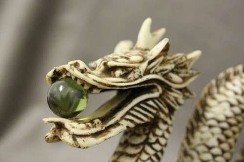 A stunning pair of Japanese ivorine resin dragons figurines with a crystal ball in their mouths