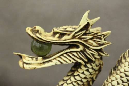 A stunning pair of Japanese ivorine resin dragons figurines with a crystal ball in their mouths
