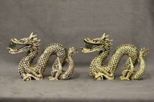 A stunning pair of Japanese ivorine resin dragons figurines with a crystal ball in their mouths
