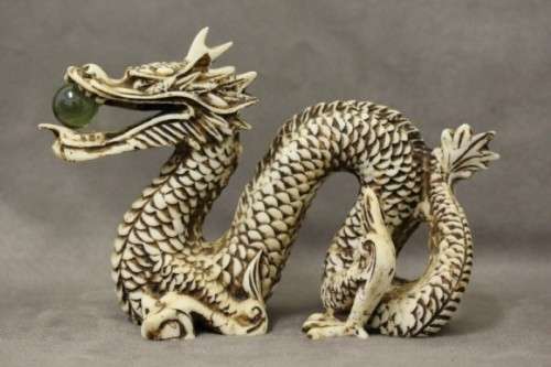A stunning pair of Japanese ivorine resin dragons figurines with a crystal ball in their mouths