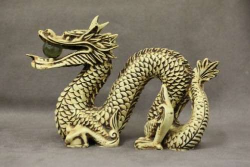 A stunning pair of Japanese ivorine resin dragons figurines with a crystal ball in their mouths