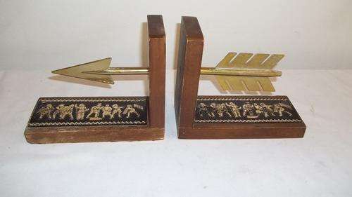 A STUNNING PAIR OF WOODEN BOOKENDS WITH A MEDIEVAL THEMED DESIGN AND BRASS ARROW ENDS