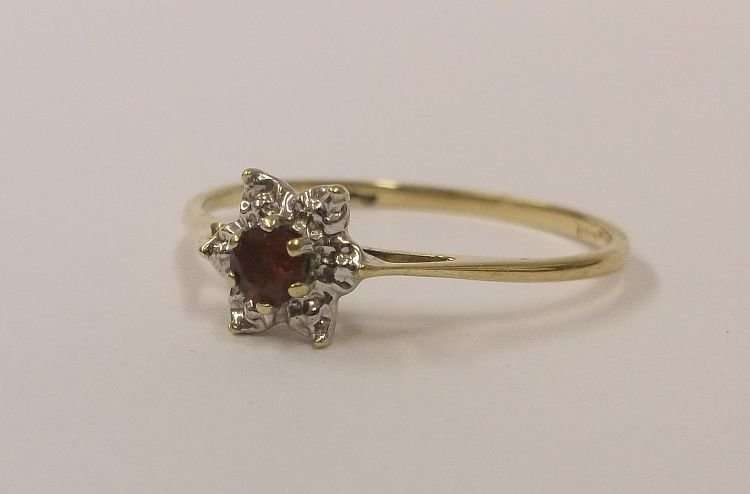 A PETITE AND CLASSIC CLUSTER LOOK RING IN 9 CT GOLD SET WITH A FACETED RED CENTER STONE
