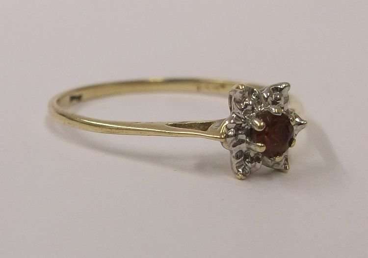 A PETITE AND CLASSIC CLUSTER LOOK RING IN 9 CT GOLD SET WITH A FACETED RED CENTER STONE