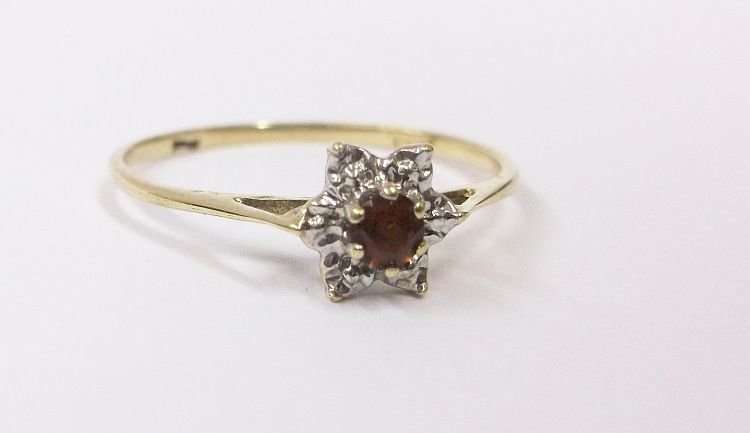 A PETITE AND CLASSIC CLUSTER LOOK RING IN 9 CT GOLD SET WITH A FACETED RED CENTER STONE