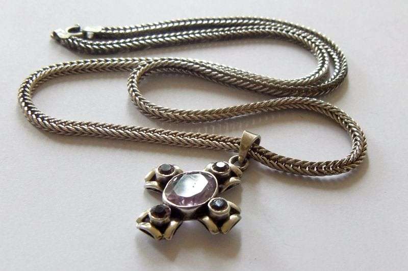 A STRONG AND STURDY "WEAVED" STERLING SILVER NECKLACE WITH A FACETED PURPLE STONE SET SILVER CROSS