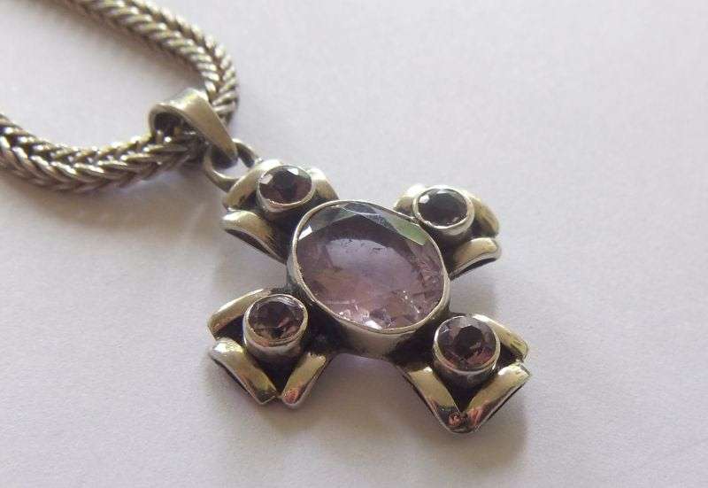 A STRONG AND STURDY "WEAVED" STERLING SILVER NECKLACE WITH A FACETED PURPLE STONE SET SILVER CROSS