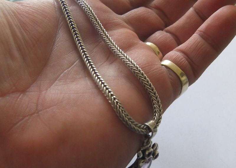 A STRONG AND STURDY "WEAVED" STERLING SILVER NECKLACE WITH A FACETED PURPLE STONE SET SILVER CROSS