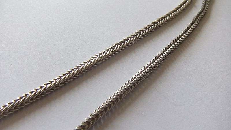 A STRONG AND STURDY "WEAVED" STERLING SILVER NECKLACE WITH A FACETED PURPLE STONE SET SILVER CROSS