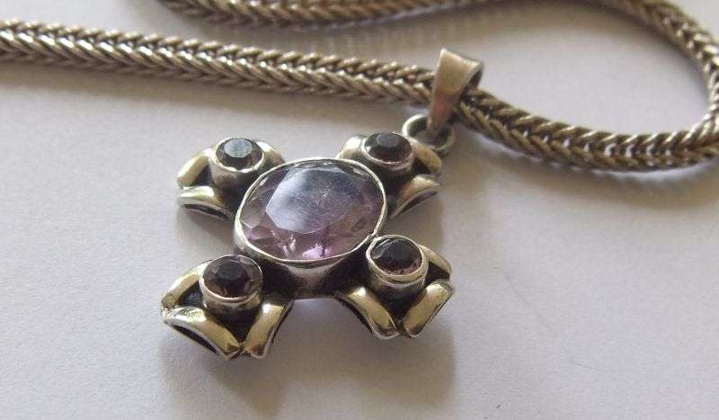 A STRONG AND STURDY "WEAVED" STERLING SILVER NECKLACE WITH A FACETED PURPLE STONE SET SILVER CROSS