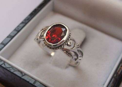 A STRIKING STERLING SILVER RING SET WITH A FACETED RED STONE - SIZE L AND A HALF