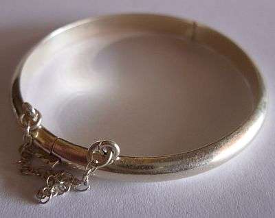 A VINTAGE STERLING SILVER CHILD BANGLE WITH SAFETY CHAIN - GREAT CONDITION