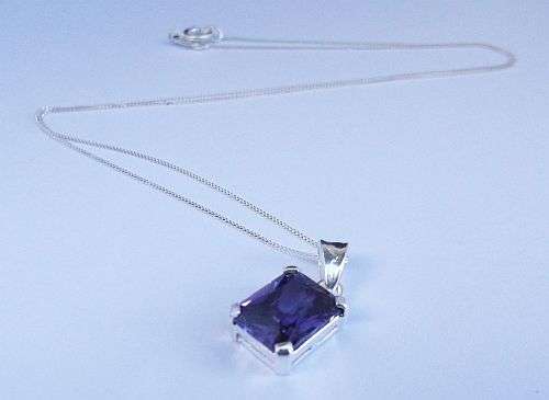 A DAINTY STERLING SILVER NECKLACE WITH AN EYE CATCHING FACETED PURPLE STONE SET PENDANT ...BAIE MOOI