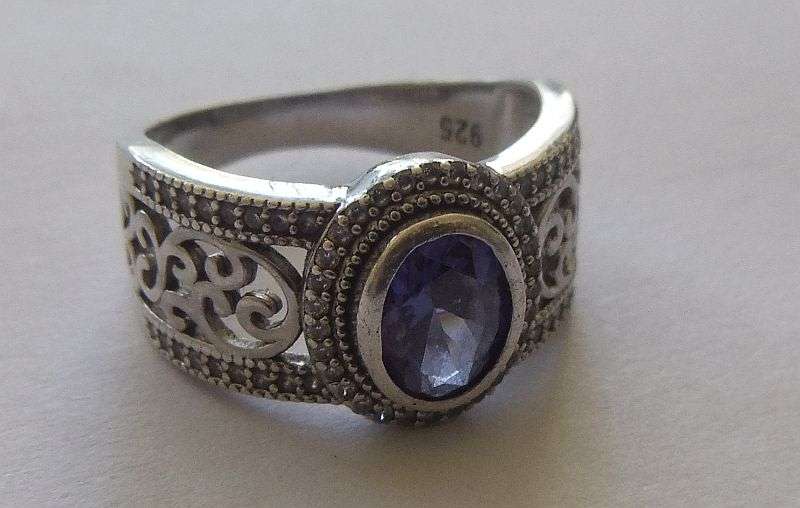 AN EXQUISITE SOLID STERLING SILVER RING SET WITH A FACETED BLUE STONE AND TINY CLEAR FACETED STONES