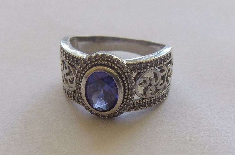 AN EXQUISITE SOLID STERLING SILVER RING SET WITH A FACETED BLUE STONE AND TINY CLEAR FACETED STONES