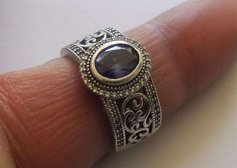 AN EXQUISITE SOLID STERLING SILVER RING SET WITH A FACETED BLUE STONE AND TINY CLEAR FACETED STONES