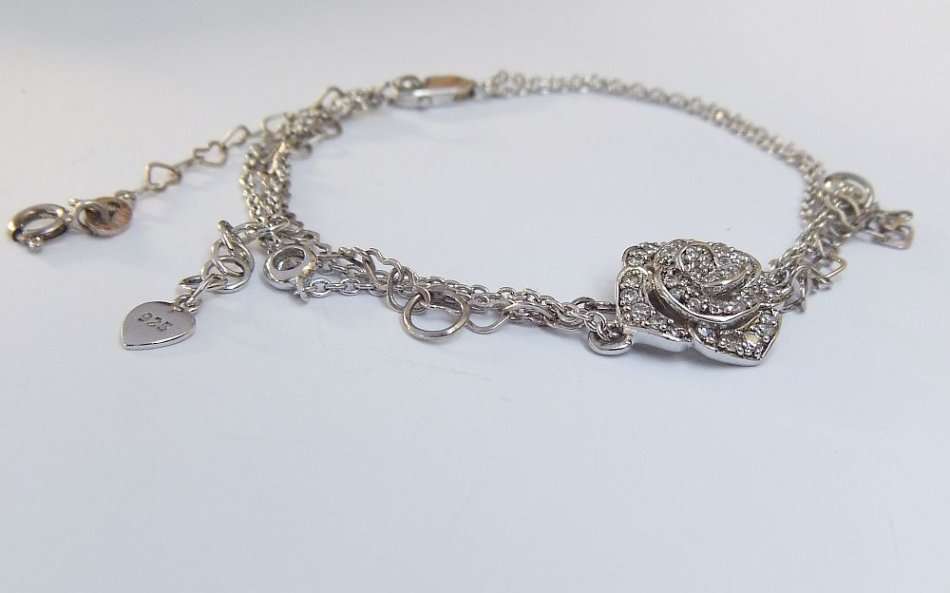 A SOLID STERLING SILVER BRACELET WITH FACETED CZ SET FLORAL FEATURE - STAMPED AND TESTED