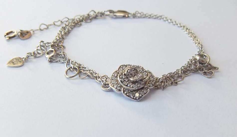 A SOLID STERLING SILVER BRACELET WITH FACETED CZ SET FLORAL FEATURE - STAMPED AND TESTED