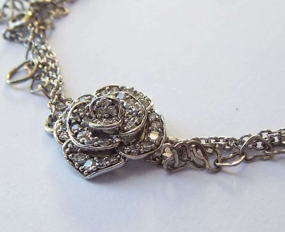 A SOLID STERLING SILVER BRACELET WITH FACETED CZ SET FLORAL FEATURE - STAMPED AND TESTED