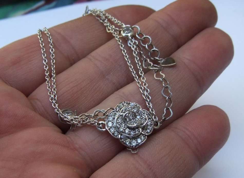 A SOLID STERLING SILVER BRACELET WITH FACETED CZ SET FLORAL FEATURE - STAMPED AND TESTED