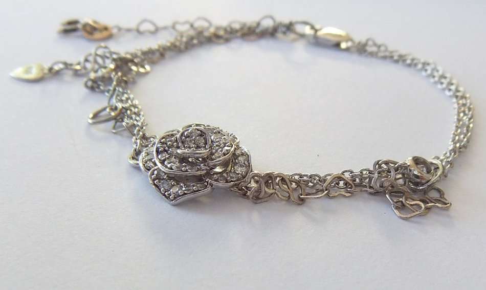 A SOLID STERLING SILVER BRACELET WITH FACETED CZ SET FLORAL FEATURE - STAMPED AND TESTED