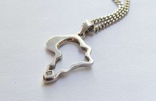 A COOL SOLID STERLING SILVER AFRICA PENDANT SET WITH A FACETED STONE PLUS A STERLING SILVER NECKLACE