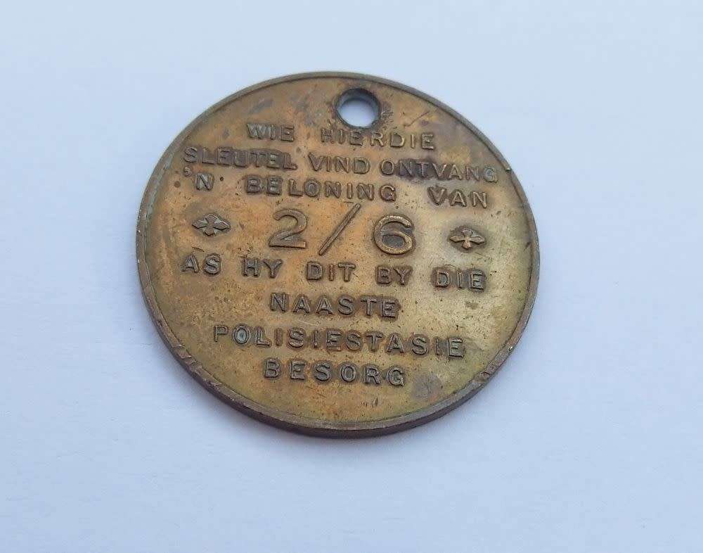 A vintage South African Post Office lost key token entitling the finder to 2 shillings and 6 pence