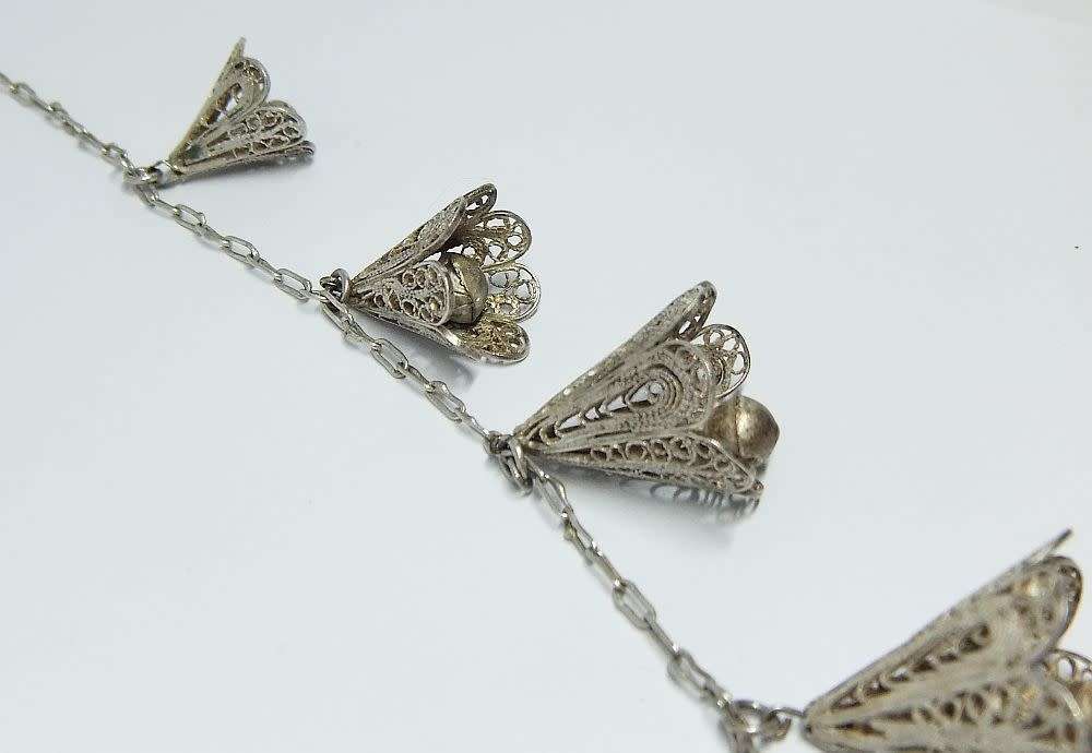 A vintage sterling silver necklace with silver filigree bell attachments
