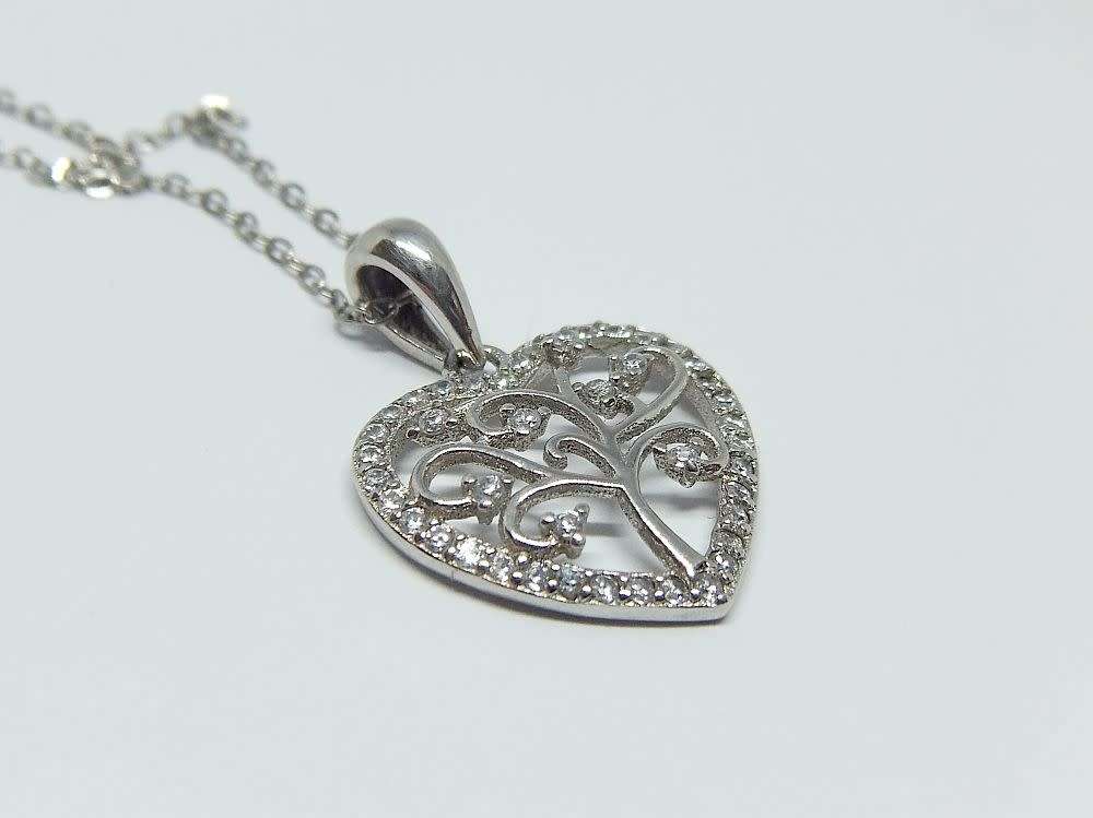 A genuine sterling silver necklace and heart pendant containing the tree of life with clear insets