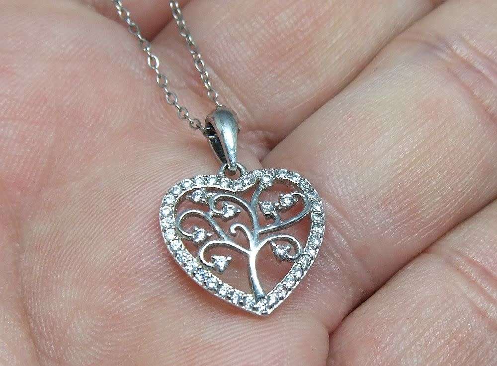 A genuine sterling silver necklace and heart pendant containing the tree of life with clear insets