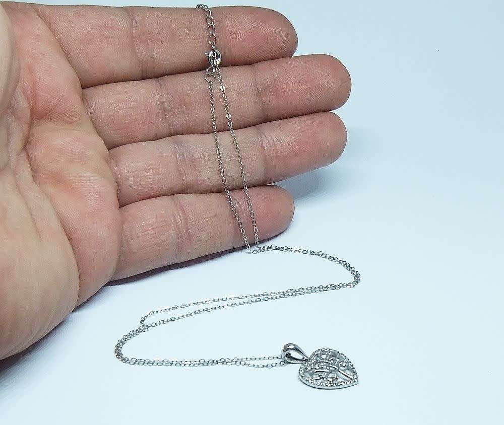 A genuine sterling silver necklace and heart pendant containing the tree of life with clear insets