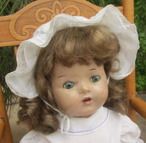 VINTAGE RELIABLE COMPOSITION DOLL DRESSED IN A VINTAGE BONNET AND SMOCKED DRESS