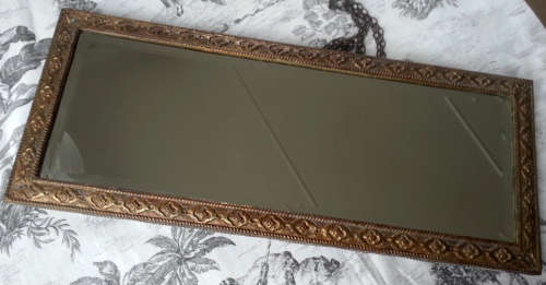 ANTIQUE, RECTANGULAR BEVELED MIRROR SET WITHIN A DECORATIVE PRESSED METAL FRAME