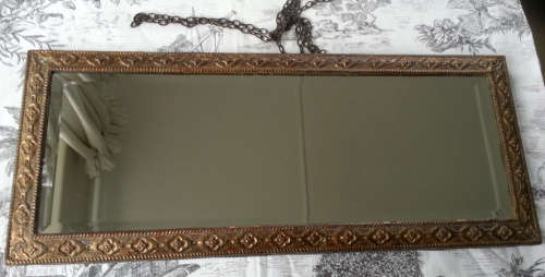 ANTIQUE, RECTANGULAR BEVELED MIRROR SET WITHIN A DECORATIVE PRESSED METAL FRAME