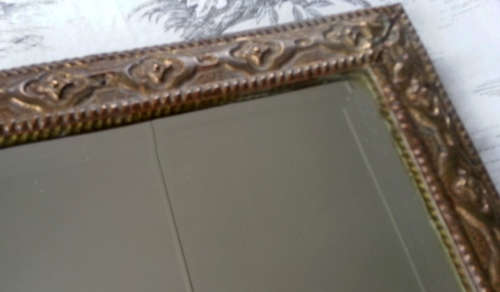 ANTIQUE, RECTANGULAR BEVELED MIRROR SET WITHIN A DECORATIVE PRESSED METAL FRAME