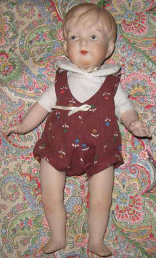 VINTAGE PORCELAIN, BOY DOLL DRESSED IN A SHIRT AND ROMPERS, NEEDS RESTRINGING.