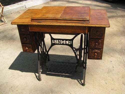 AN ANTIQUE SINGER SEWING MACHINE IN ORNATE CAST IRON AND OAK CABINET