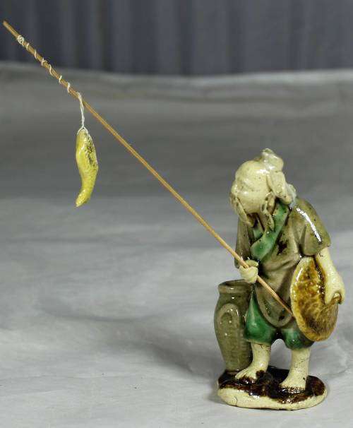 Mud Men - Old man holding a fish and hat