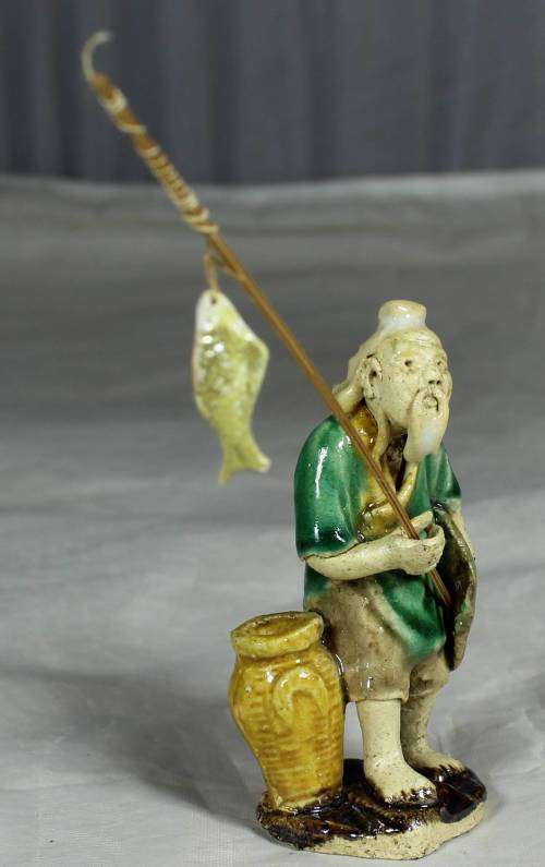 Mud Men - Old man holding a fish and hat