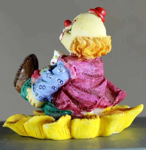 Small clown figurine seated on a sunflower