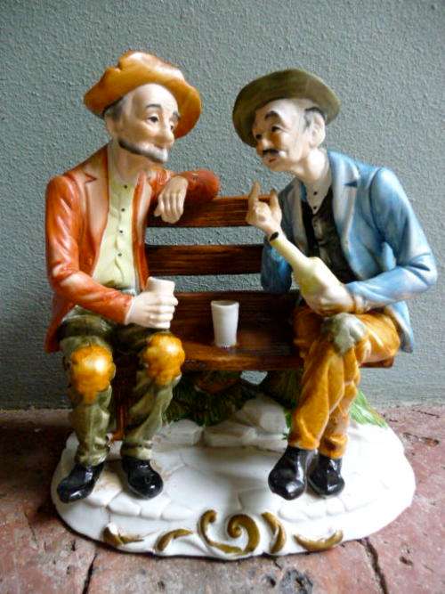 Striking detail, old men drinking on bench statue.