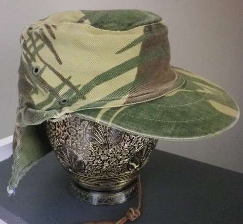 RHODESIAN -  CAMO CAP - PART OF FLAP CUT OFF BY OWNER - HAS ORIGINAL ORANGE LINING -  (5454)