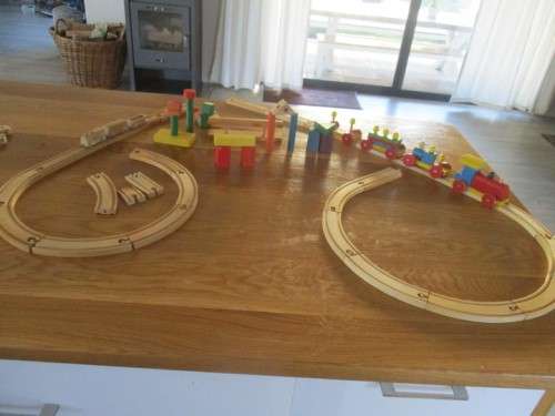 A BAG FULL OF VINTAGE WOODEN TOYS INCLUDING TWO LOCOMOTIVES WITH CARRIAGES, TRACKS AND WOODEN BLOCKS