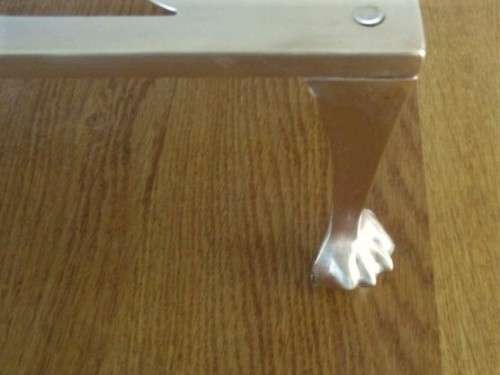 A LARGE ANTIQUE BRASS FIRE HEARTH TRIVET WITH BALL AND CLAW FEET