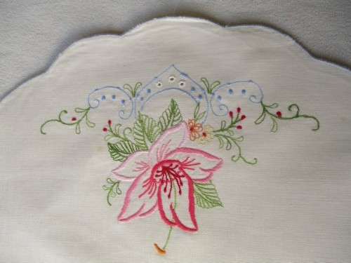 A SET OF TWO SMALL, ROUND VINTAGE HAND EMBROIDERED CLOTHS/DOILIES WITH LILY DESIGN