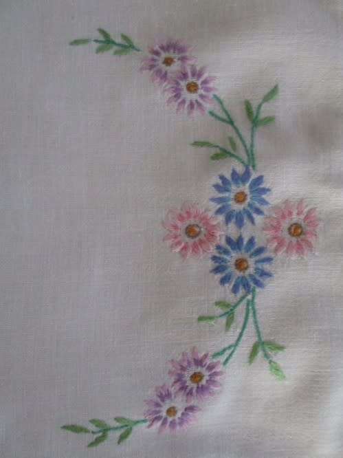 A VINTAGE RECTANGULAR HAND EMBROIDERED CLOTH WITH PRETTY PINK, BLUE AND LAVENDER DAISIES