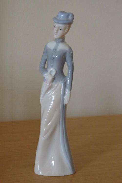 A BEAUTIFUL AND VERY ELEGANT PORCELAIN FIGURINE OF A SLENDER LADY WITH HER UMBRELLA