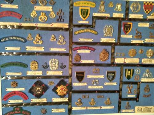 Display of South African Traditional Regiments cap/beret badges, shoulder titles and collar badges.