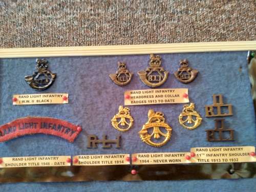 Display of South African Traditional Regiments cap/beret badges, shoulder titles and collar badges.